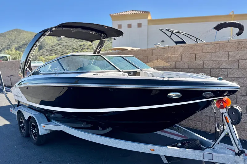Slide: The Image of 2019 Regal 2100 boat on trailer, sleek black design, parked outdoors. - 1