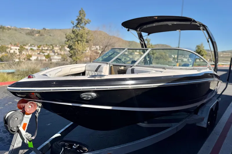 Slide: The Image of 2019 Regal 2100 boat on trailer, parked outdoors with scenic background. - 3