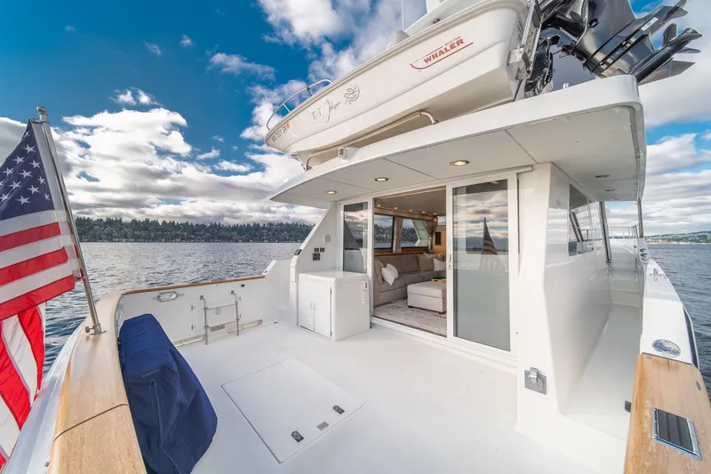 Slide: The Image of 1995 Tollycraft 57 Walk Around Pilothouse yacht with American flag, spacious deck, and scenic water view. - 46