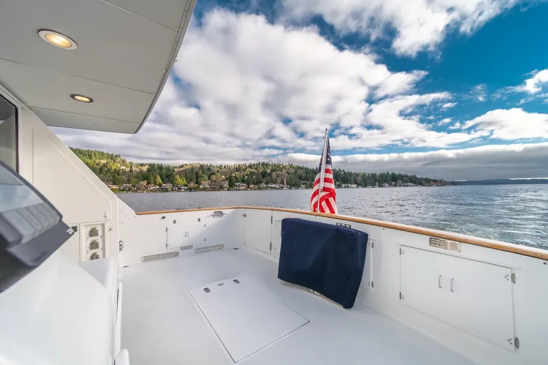 Slide: The Image of 1995 Tollycraft 57 Walk Around Pilothouse yacht deck with American flag, scenic lake view. - 51