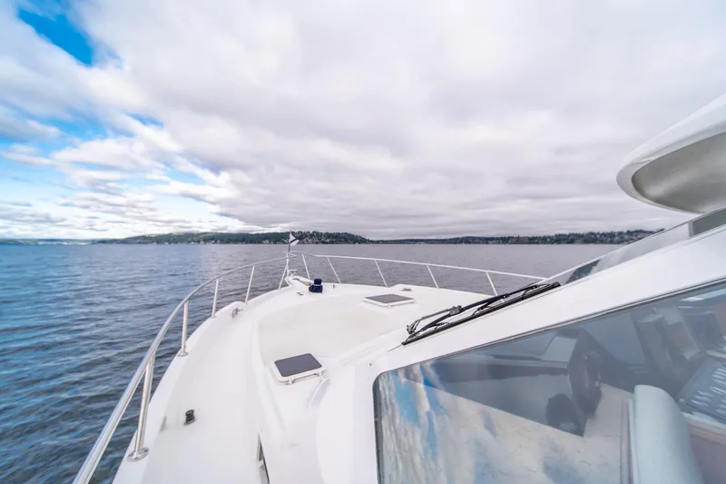Slide: The Image of 1995 Tollycraft 57 Walk Around Pilothouse yacht cruising on open water under cloudy skies. - 52