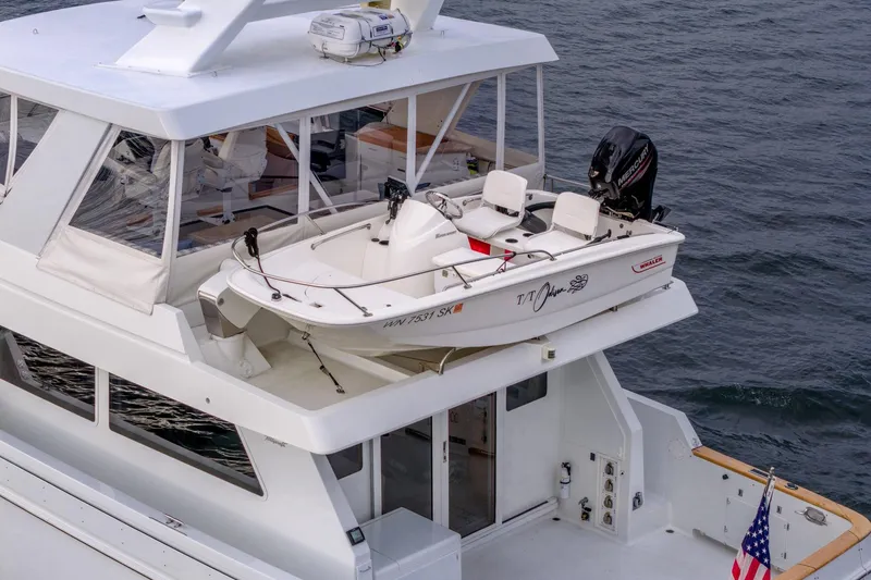 Slide: The Image of 1995 Tollycraft 57 Walk Around Pilothouse with a small boat on deck, ocean backdrop. - 59