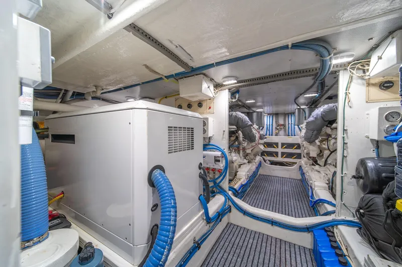 Slide: The Image of Engine room of 1995 Tollycraft 57 Walk Around Pilothouse with machinery and blue hoses. - 64