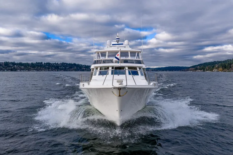Slide: The Image of 1995 Tollycraft 57 Walk Around Pilothouse yacht cruising on a scenic lake under cloudy skies. - 9