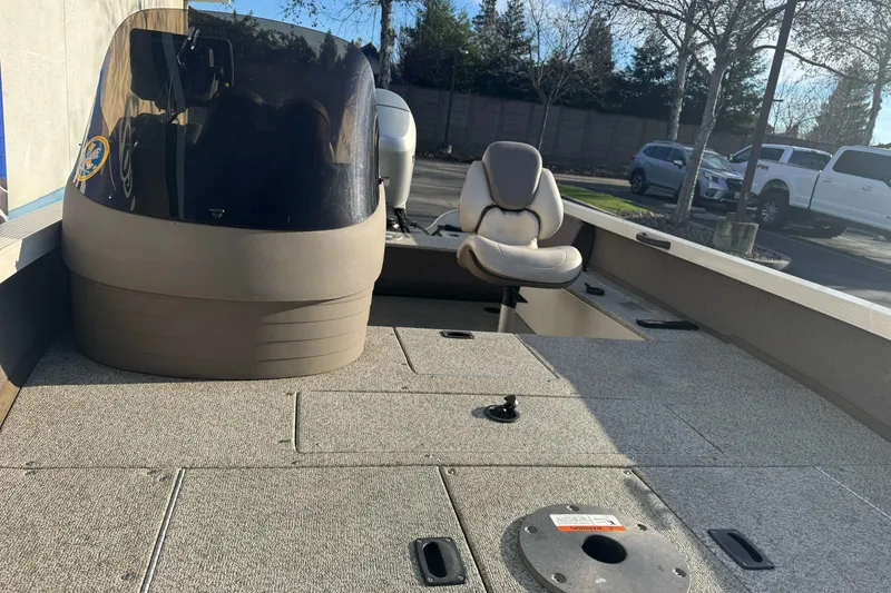 Slide: The Image of 2004 Crestliner 1650 Fish Hawk boat interior with seating and console, parked outdoors. - 10