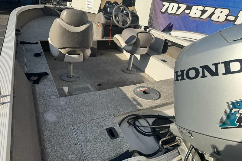 Slide: The Image of 2004 Crestliner 1650 Fish Hawk boat interior with Honda outboard motor, featuring seating and steering console. - 6