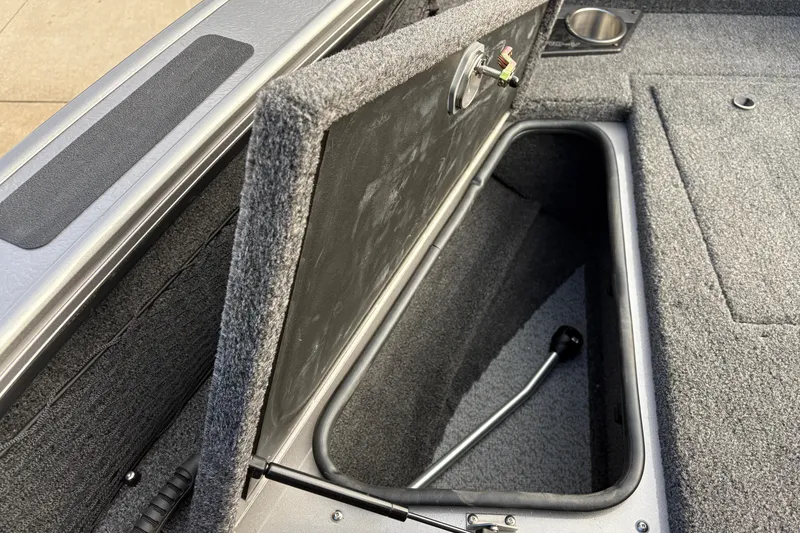 Slide: The Image of Open storage compartment in 2026 Lund 1975 Pro-V Sport boat, featuring carpeted interior. - 11