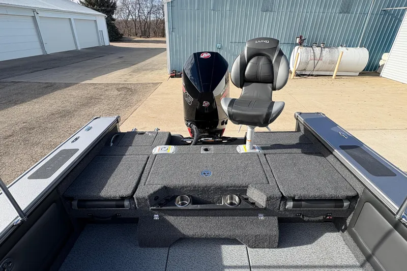 Slide: The Image of 2026 Lund 1975 Pro-V Sport boat interior with seating and motor, parked outdoors. - 35