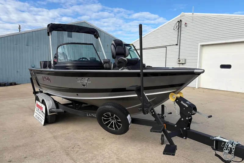 Slide: The Image of 2026 Lund 1975 Pro-V Sport boat on trailer, parked outside a warehouse. - 8