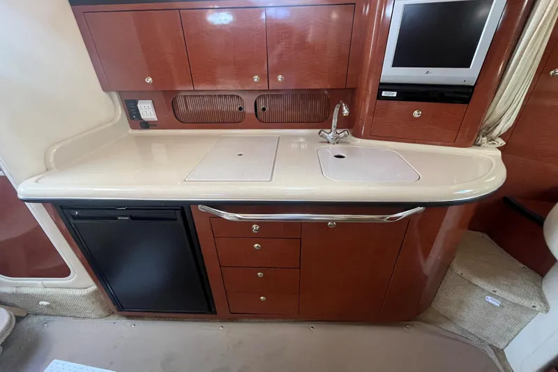 Slide: The Image of 2004 Sea Ray 340 Sundancer kitchen with sink, cabinets, and TV. - 12