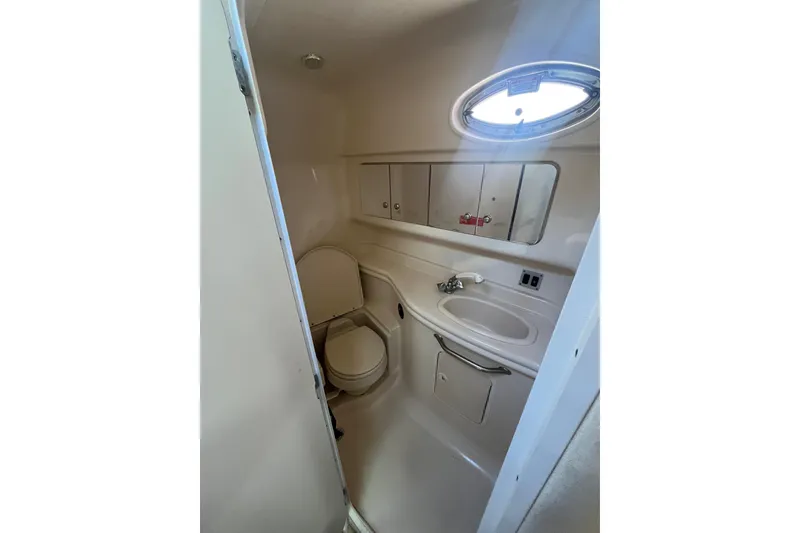 Slide: The Image of 2004 Sea Ray 340 Sundancer bathroom with sink, toilet, and porthole window. - 19