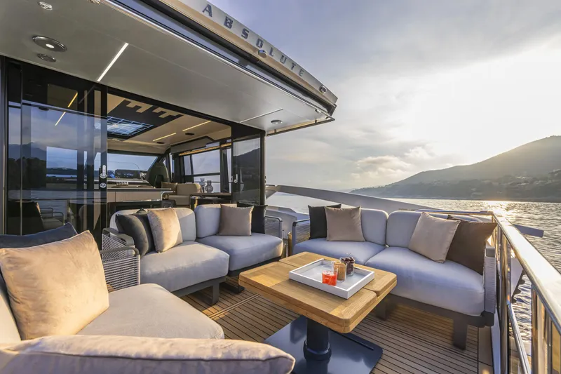 Slide: The Image of 2024 Absolute 48 Coupe yacht with luxurious outdoor seating area at sunset. - 6