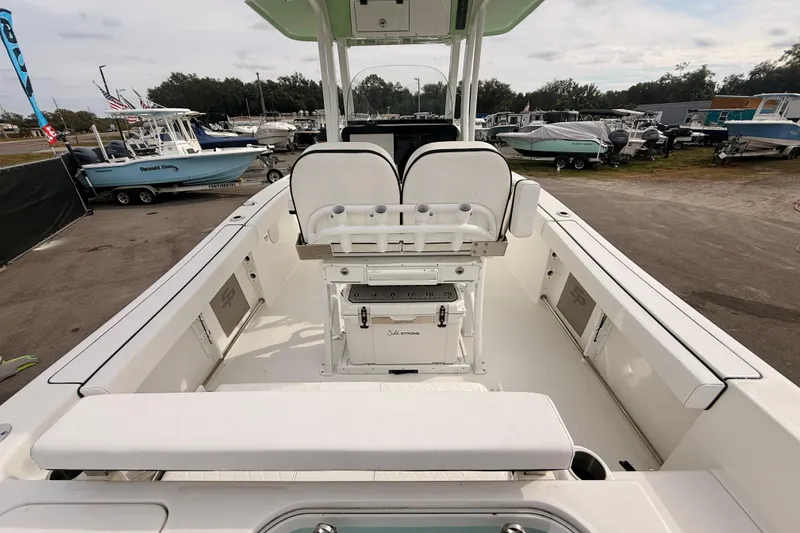 Slide: The Image of 2023 Sea Pro 239 Center Console boat interior with seating and storage, docked outdoors. - 14