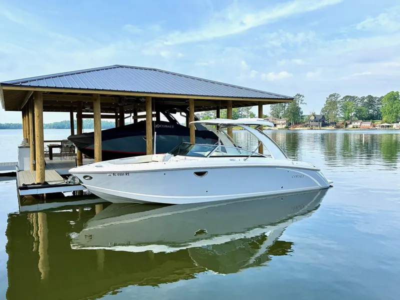 Slide: The Image of 2021 Cobalt R30 boat docked on a serene lake under a wooden shelter. - 2
