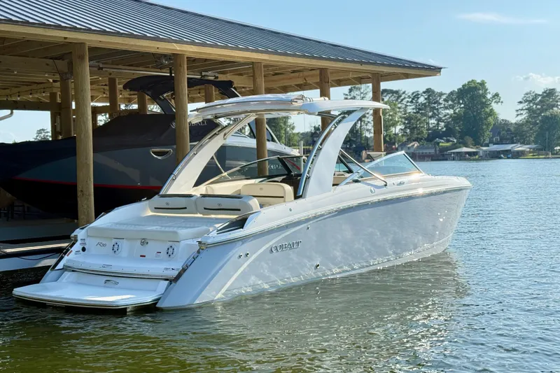 Slide: The Image of 2021 Cobalt R30 boat docked on a sunny lake with a covered boathouse. - 3