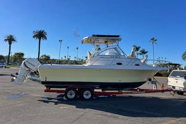 Slide: The Image of 1998 Pro-Line 2610 Walkaround boat on trailer, parked in sunny lot with palm trees. - 26