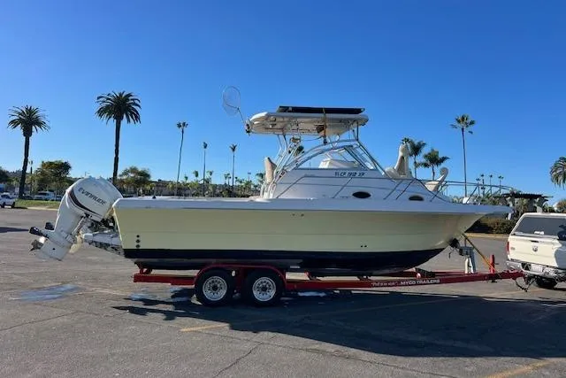 Slide: The Image of 1998 Pro-Line 2610 Walkaround boat on trailer, parked outdoors under clear blue sky. - 27