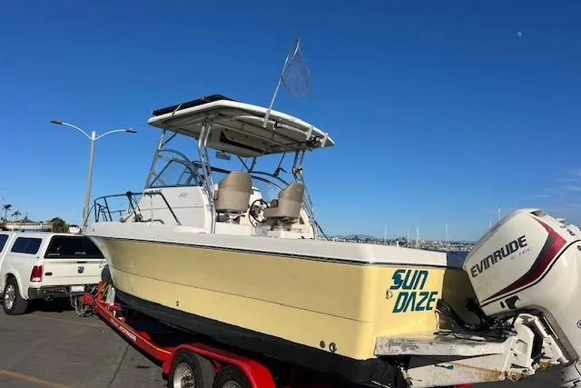 Slide: The Image of 1998 Pro-Line 2610 Walkaround boat on trailer, with Evinrude outboard motor, parked near waterfront. - 33