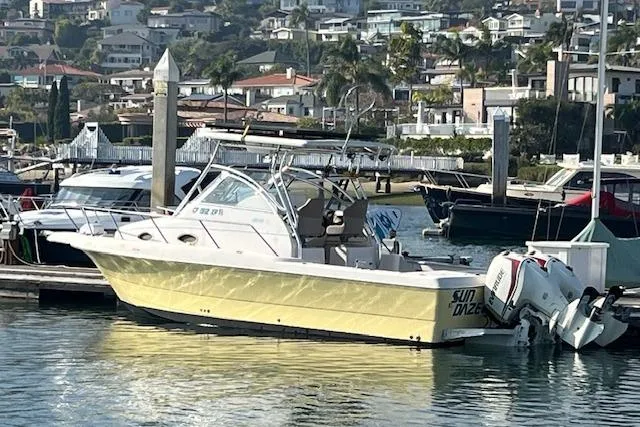 Slide: The Image of 1998 Pro-Line 2610 Walkaround boat docked in a marina, with scenic coastal background. - 7