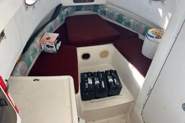 Slide: The Image of 1998 Pro-Line 2610 Walkaround cabin interior with red cushions and batteries. - 9