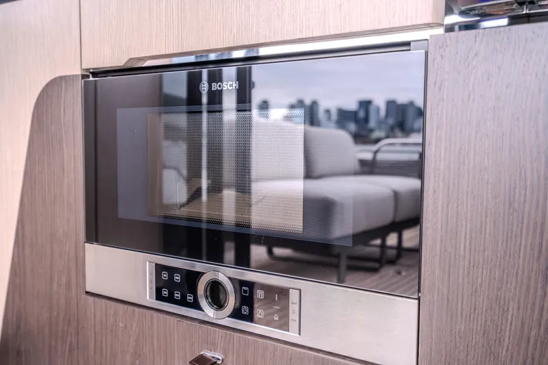 Slide: The Image of Built-in Bosch microwave in Absolute 48 Coupe yacht, 2026 model, with cityscape reflection. - 32