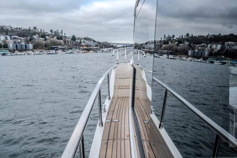 Slide: The Image of 2026 Absolute 48 Coupe yacht cruising on a scenic waterway with cityscape views. - 48