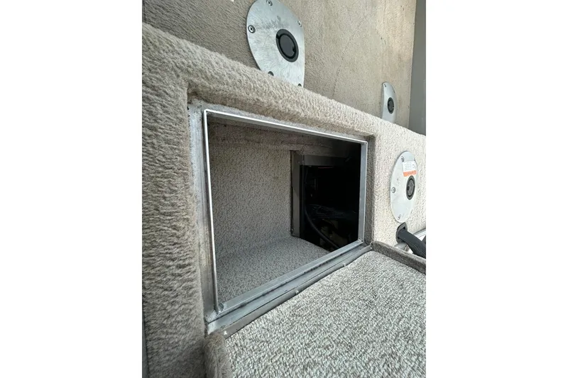 Slide: The Image of 2003 Lund 1650 Explorer SS boat storage compartment with carpeted interior and metal trim. - 28