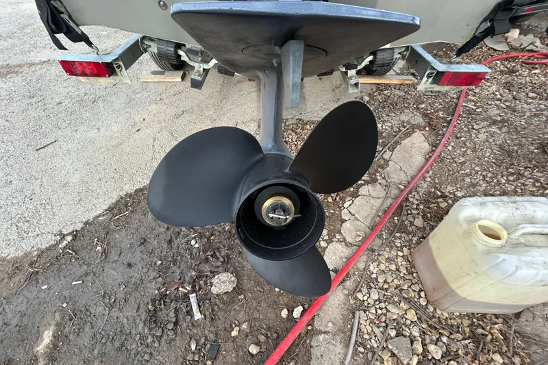 Slide: The Image of 2003 Lund 1650 Explorer SS boat propeller on trailer, surrounded by gravel and equipment. - 38