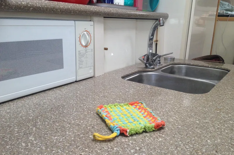 Slide: The Image of Kitchen countertop with microwave, double sink, and colorful woven mat on Maxum 3300 SCR boat. - 12