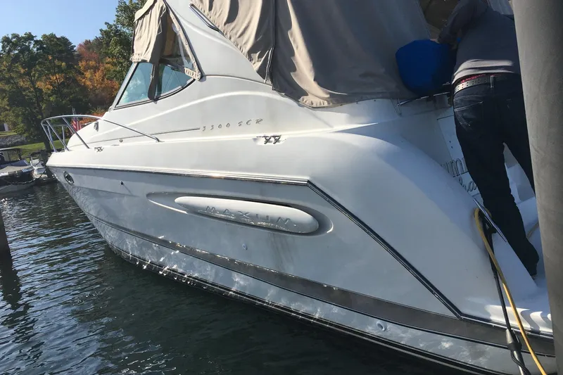 Slide: The Image of 2000 Maxum 3300 SCR boat docked, featuring sleek white design and covered cabin. - 5