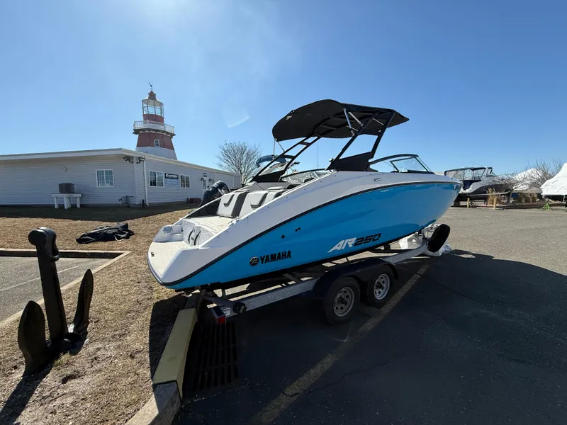 Slide: The Image of 2023 Yamaha AR250 boat on trailer near lighthouse, clear sky background. - 14