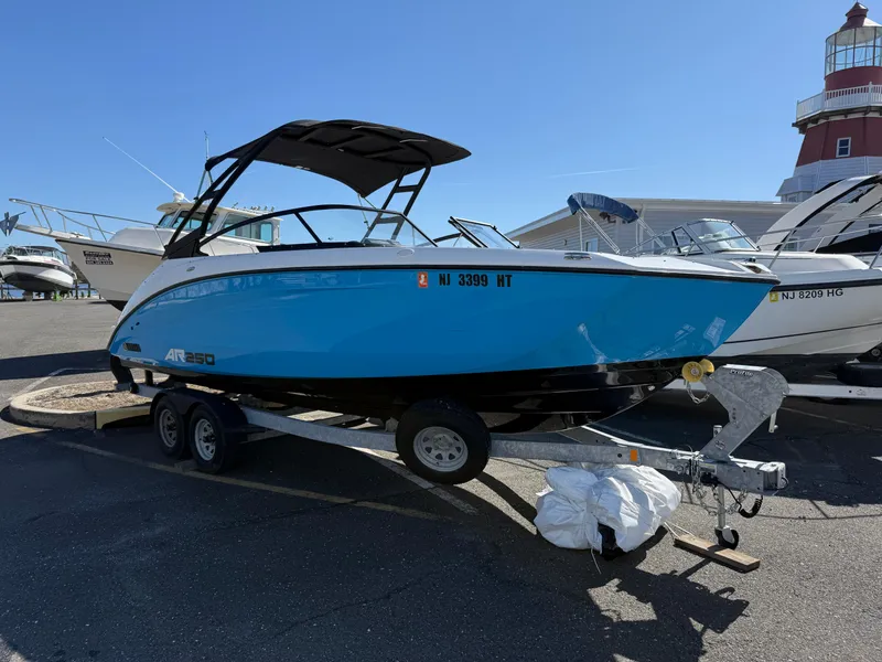 Slide: The Image of 2023 Yamaha Boats AR250 on trailer, blue and white, parked near a lighthouse. - 4