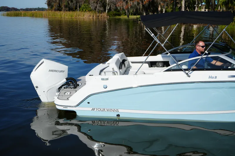 Slide: The Image of 2026 Four Winns HD3 OB boat on a calm lake with a Mercury outboard engine. - 34