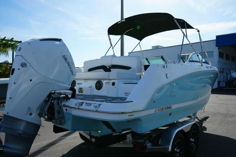 Slide: The Image of 2026 Four Winns HD3 OB boat with Mercury outboard engine, parked on a trailer. - 8