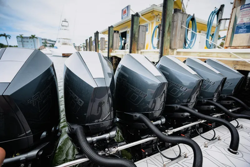 Slide: The Image of Five powerful outboard motors on a 2026 Deep Impact 499 Sport boat docked at a marina. - 49