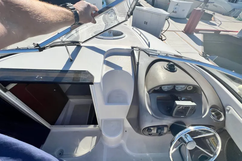 Slide: The Image of 2006 Regal Marine 2650 Cuddy boat dashboard and cabin entrance at a marina. - 13