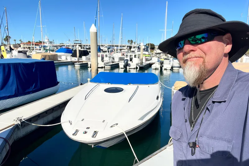Slide: The Image of Man with sunglasses and hat beside a 2006 Regal Marine 2650 Cuddy boat at marina. - 2