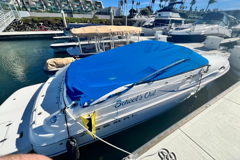 Slide: The Image of 2006 Regal Marine 2650 Cuddy boat docked with blue cover, named "School's Out." - 3