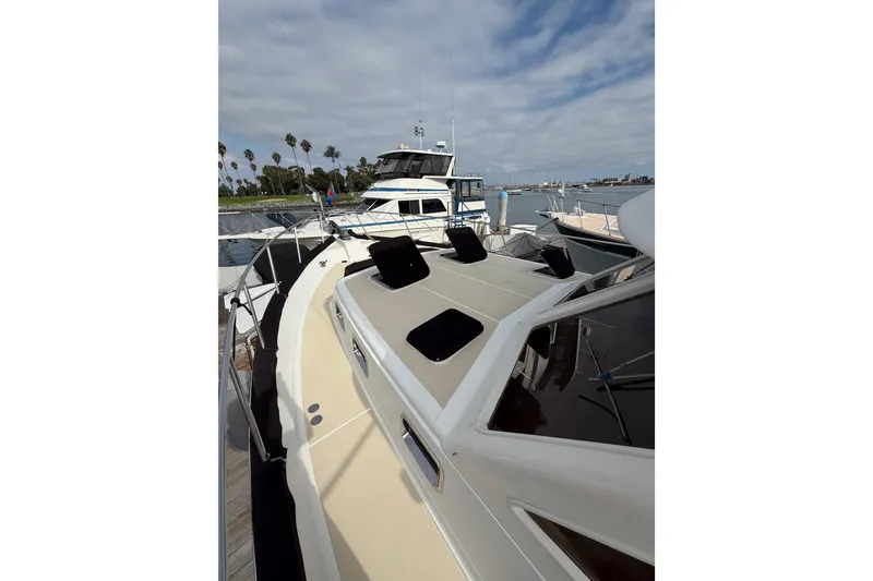 Slide: The Image of 1988 Offshore Yachts 48 Sedan docked, featuring spacious deck and sleek design under cloudy sky. - 11