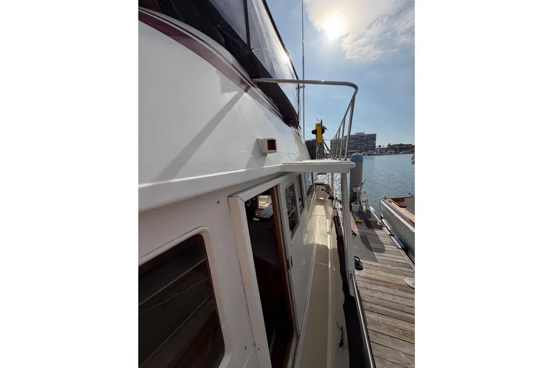 Slide: The Image of 1988 Offshore Yachts 48 Sedan docked, side view with sunny sky and water. - 16