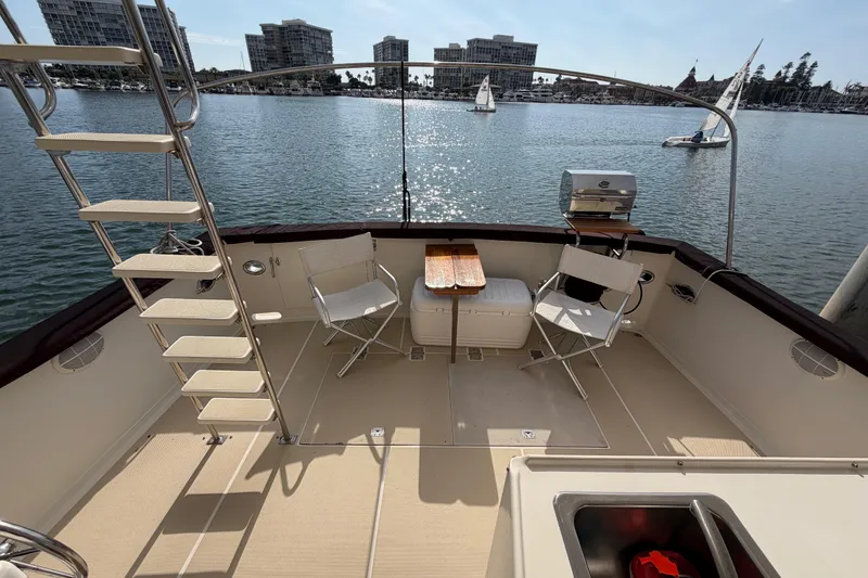 Slide: The Image of 1988 Offshore Yachts 48 Sedan deck with chairs, table, and marina view. - 17