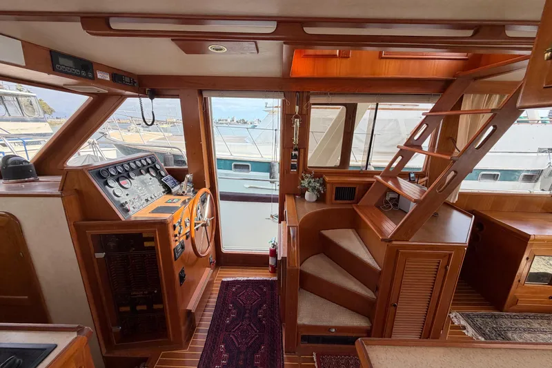 Slide: The Image of Interior of 1988 Offshore Yachts 48 Sedan, featuring helm, stairs, and wooden cabinetry. - 32