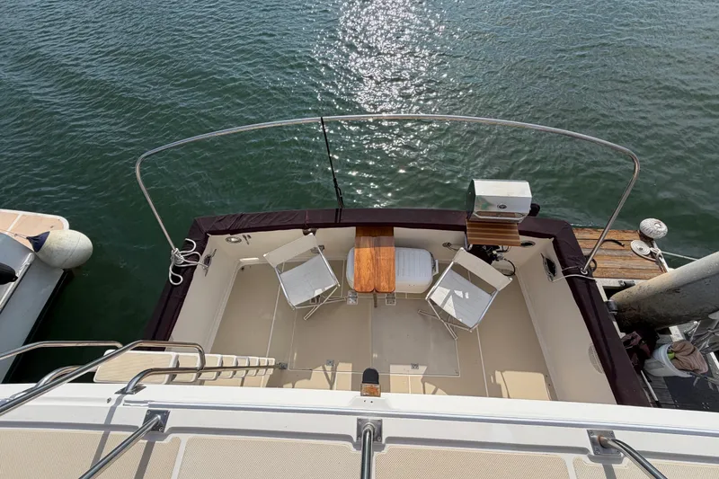 Slide: The Image of 1988 Offshore Yachts 48 Sedan, view of deck with chairs and table, docked by water. - 36
