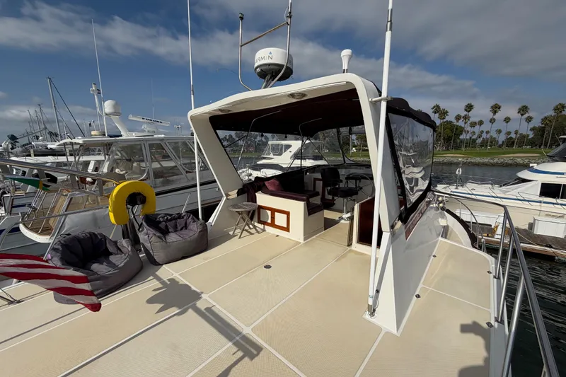 Slide: The Image of 1988 Offshore Yachts 48 Sedan docked, featuring spacious deck and seating area under clear skies. - 37