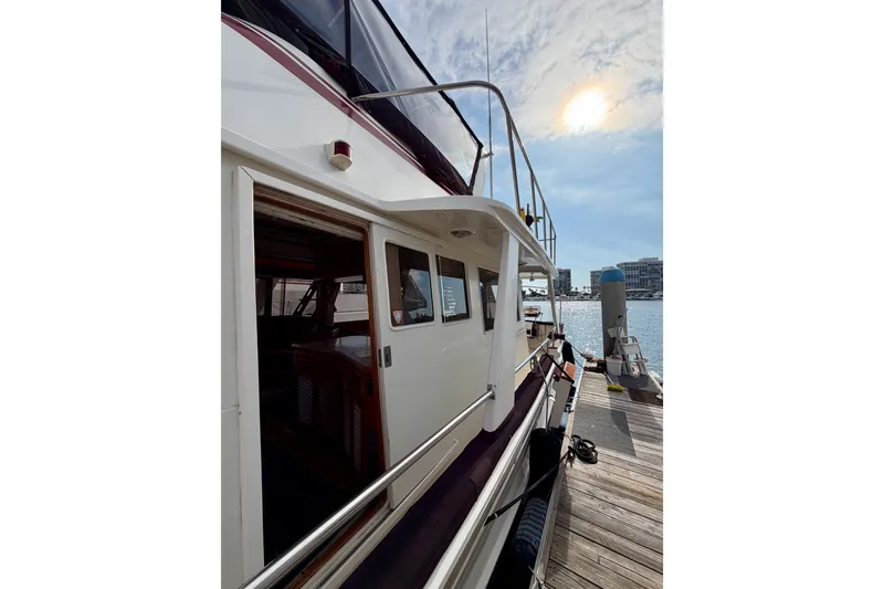 Slide: The Image of 1988 Offshore Yachts 48 Sedan docked under a sunny sky. - 4