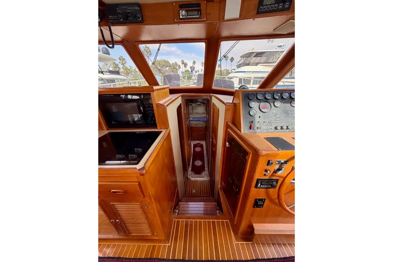 Slide: The Image of 1988 Offshore Yachts 48 Sedan interior with wooden helm and control panel. - 56