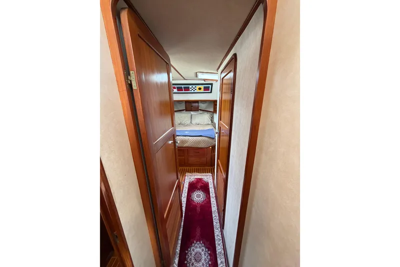 Slide: The Image of Interior hallway of 1988 Offshore Yachts 48 Sedan, featuring wood doors and cozy bedroom. - 63