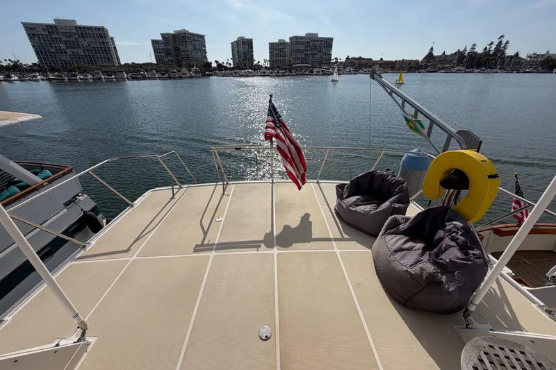 Slide: The Image of 1988 Offshore Yachts 48 Sedan deck with bean bags, overlooking marina and cityscape. - 35