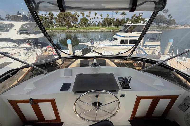 Slide: The Image of Cockpit view of 1988 Offshore Yachts 48 Sedan, docked with scenic marina backdrop. - 41