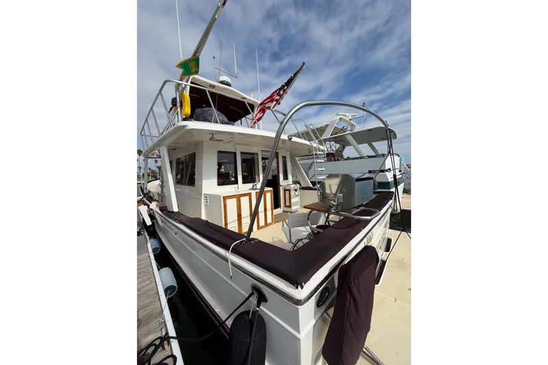 Slide: The Image of 1988 Offshore Yachts 48 Sedan docked, featuring upper deck and American flag. - 7